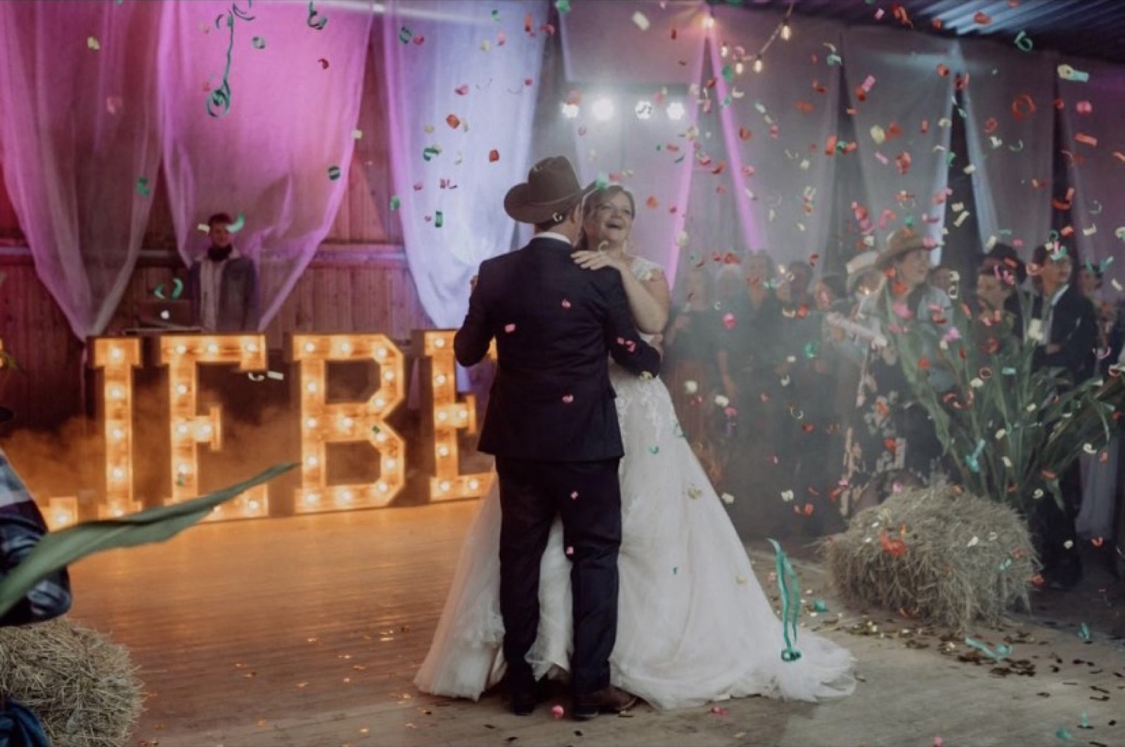 Hochzeitstanz mit Konfetti vor Leuchtbuchstaben