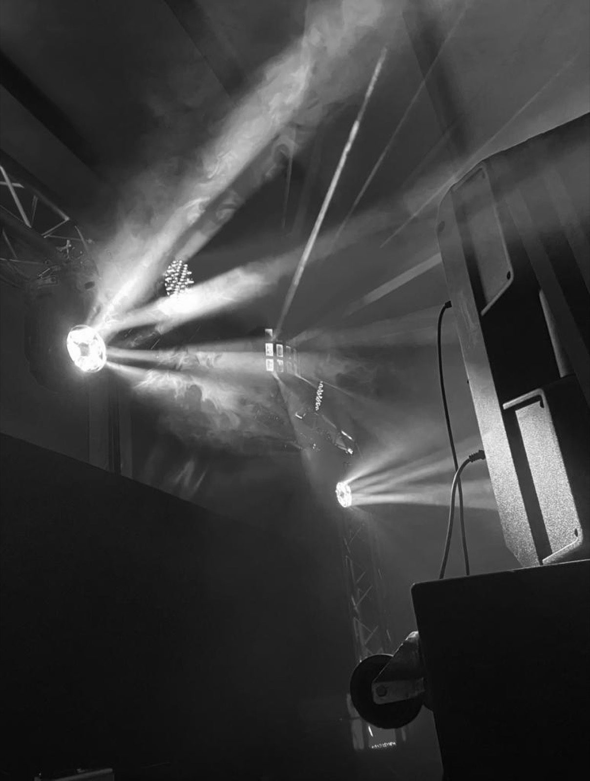 Moving Heads werfen Lichtstrahlen durch Nebel, daneben ein Lautsprecher